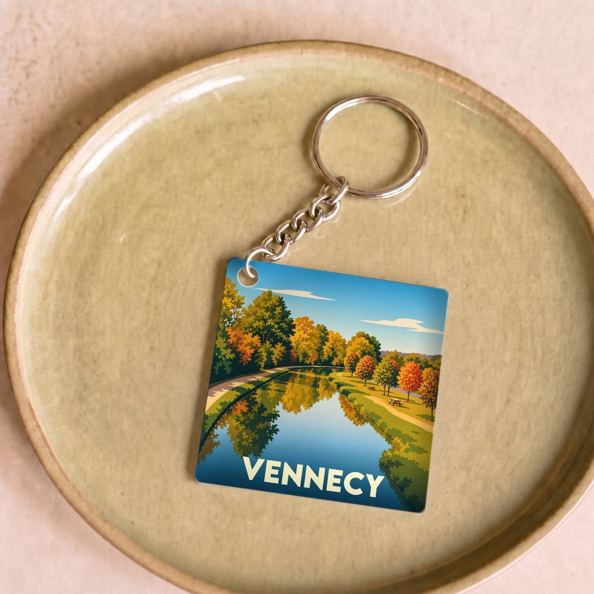Porte-clés souvenir de la ville de Vennecy avec une illustration automnale de son paysage.