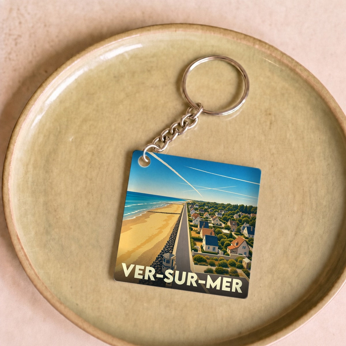 Porte-clés souvenir de la ville de Ver-sur-Mer avec une illustration stylisée du bord de mer.