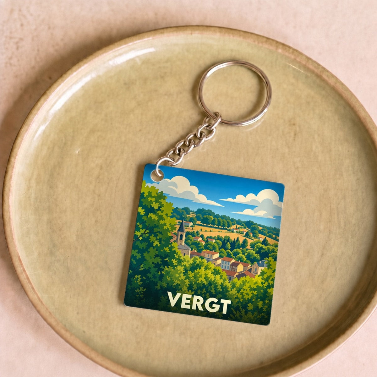 Porte-clés souvenir de la ville de Vergt avec une illustration stylisée d'un paysage vallonné.