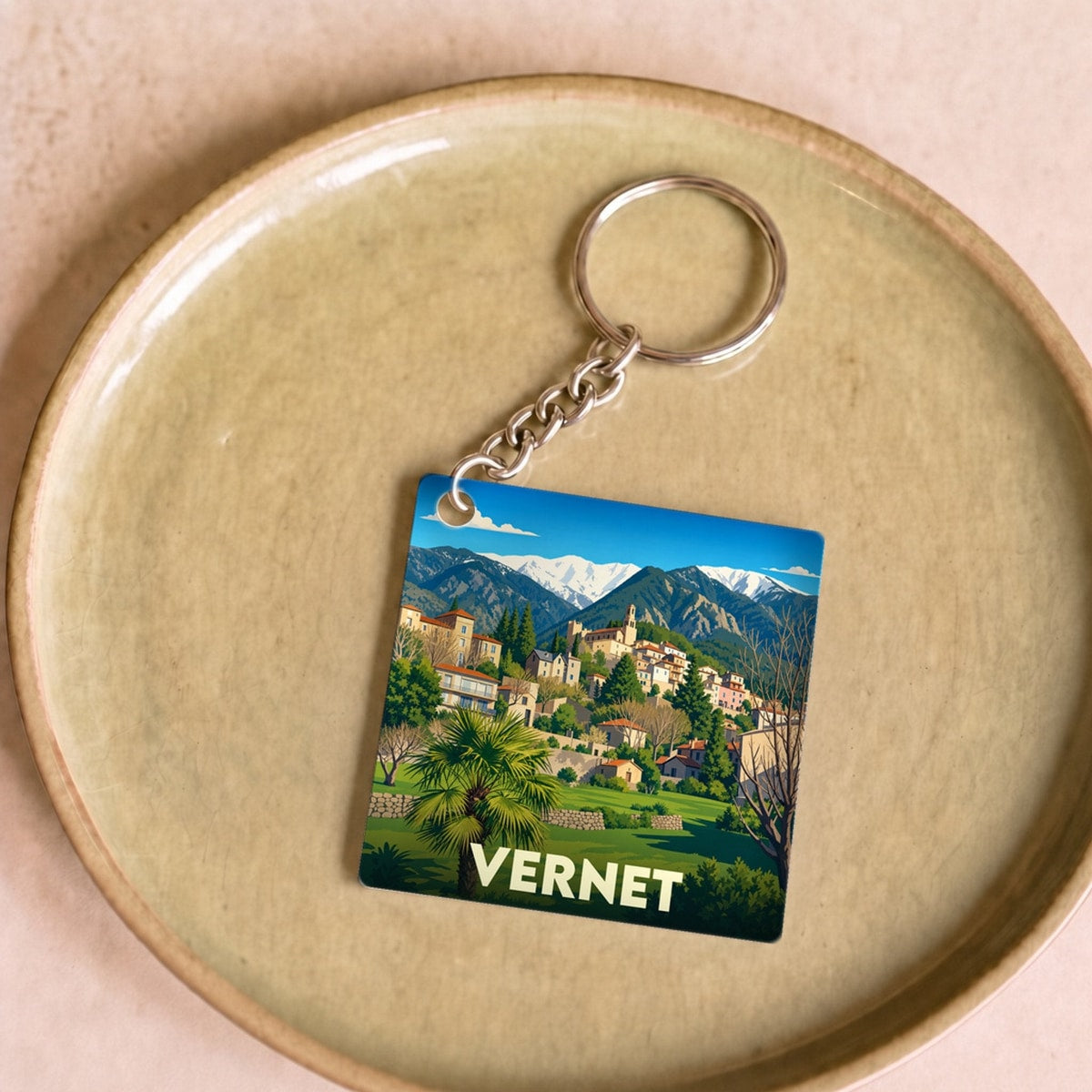 Porte-clés souvenir de la ville de Vernet avec une illustration stylisée de son paysage montagneux.