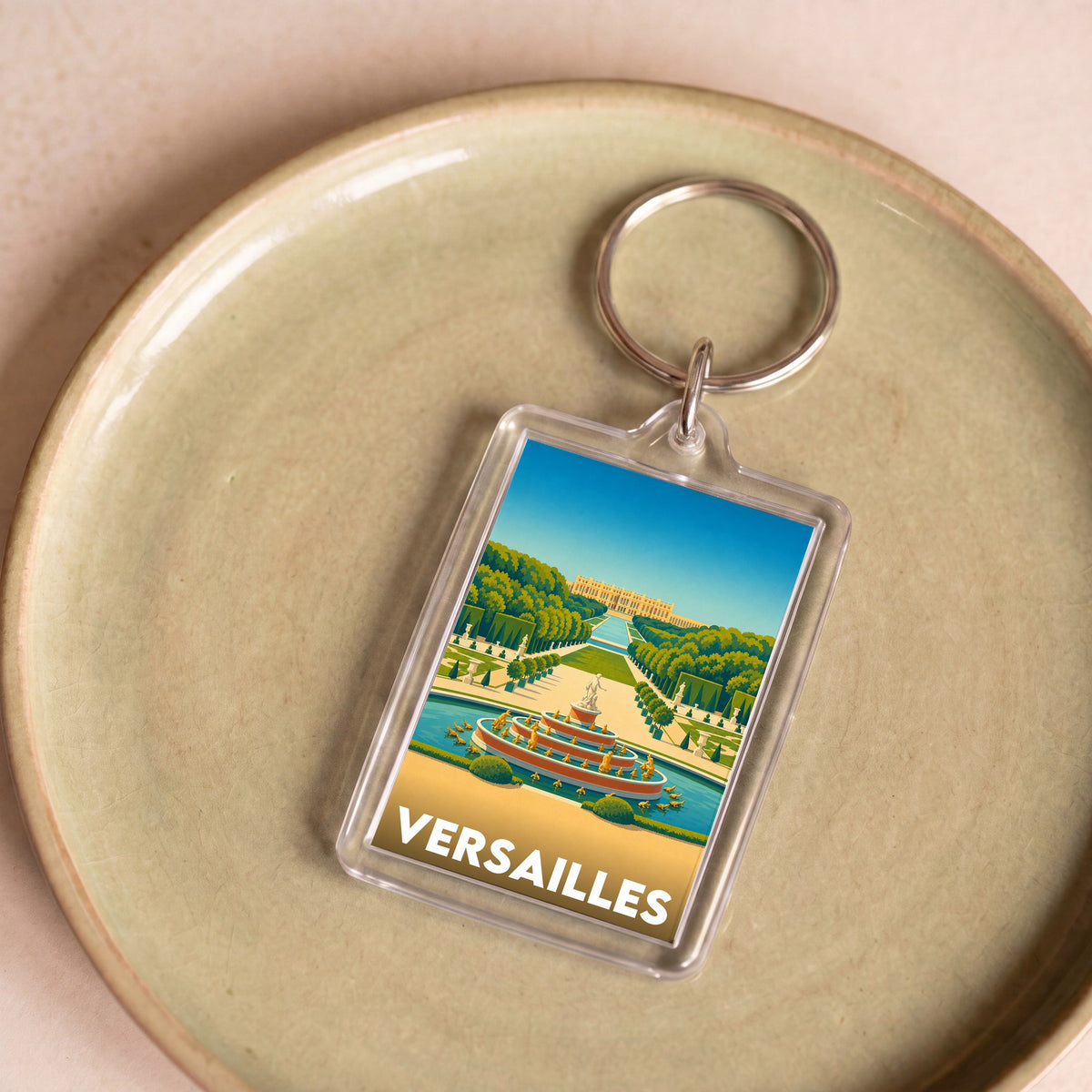 Porte-clés souvenir de la ville de Versailles avec une illustration stylisée de son château et de ses jardins.