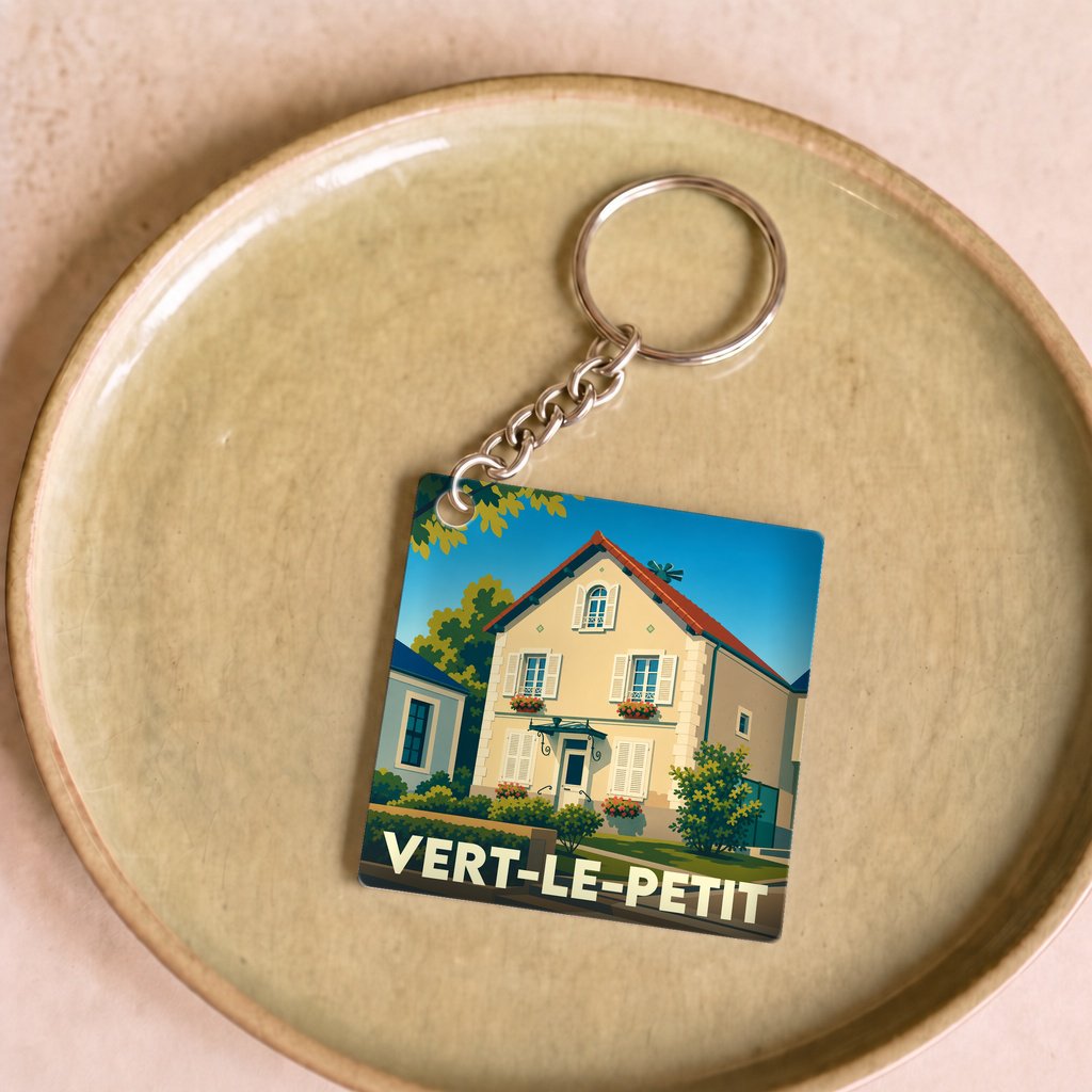 Porte-clés souvenir de la ville de Vert-le-Petit avec une illustration stylisée d'une maison de village.
