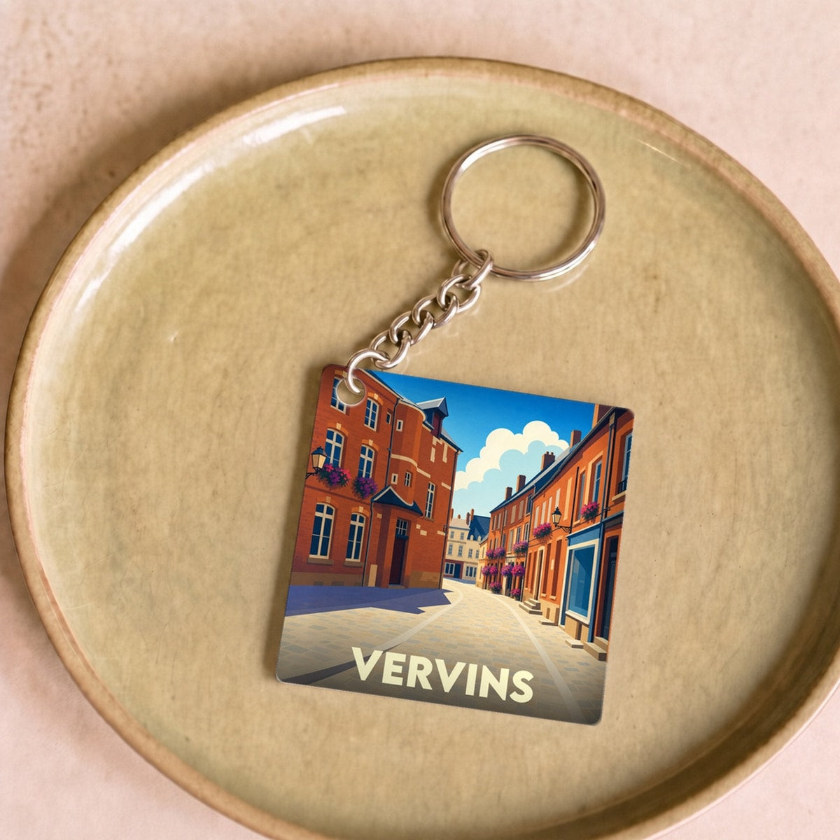 Porte-clés souvenir de la ville de Vervins avec une illustration stylisée d'une rue pittoresque.