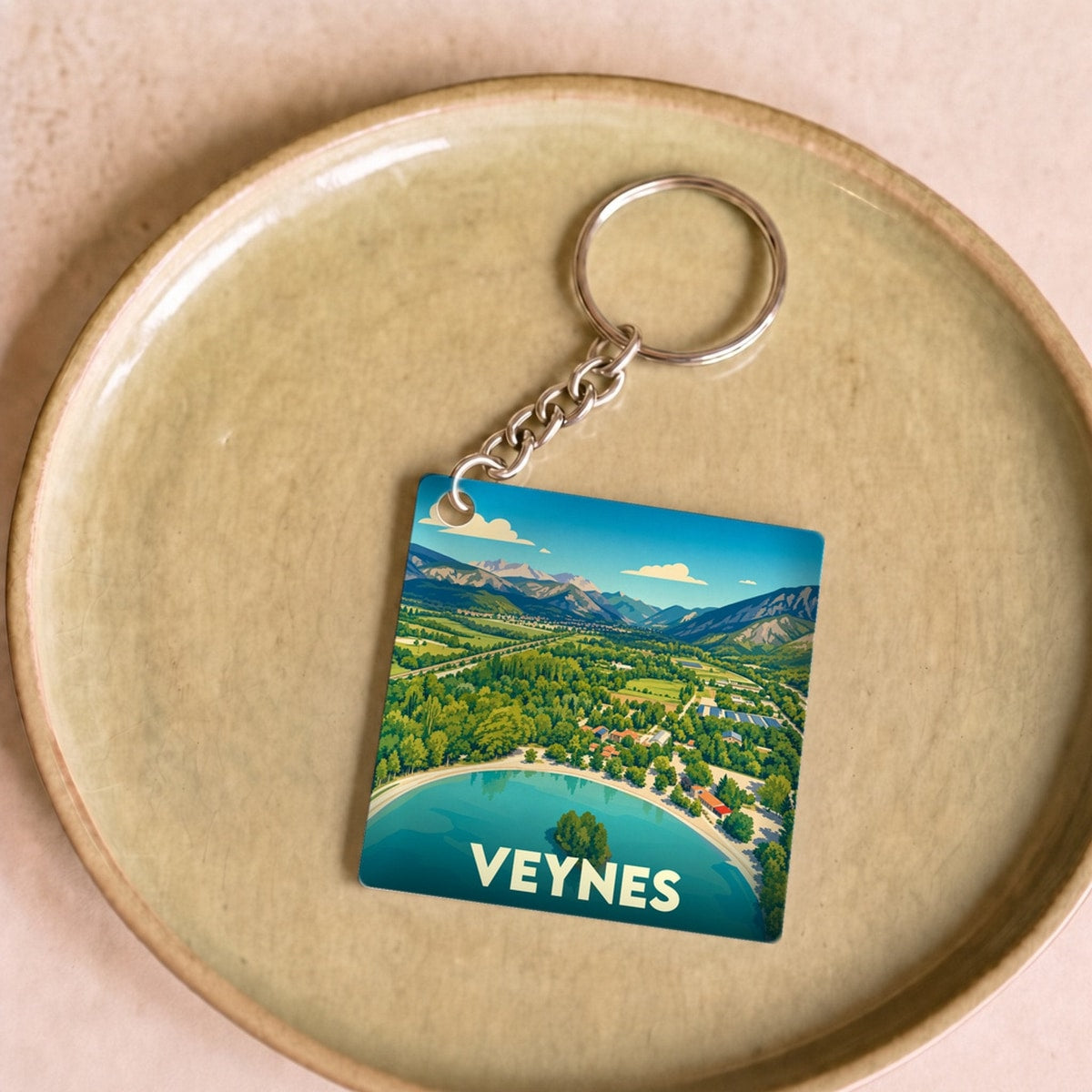 Porte-clés souvenir de la ville de Veynes avec une illustration stylisée d'un lac de montagne.