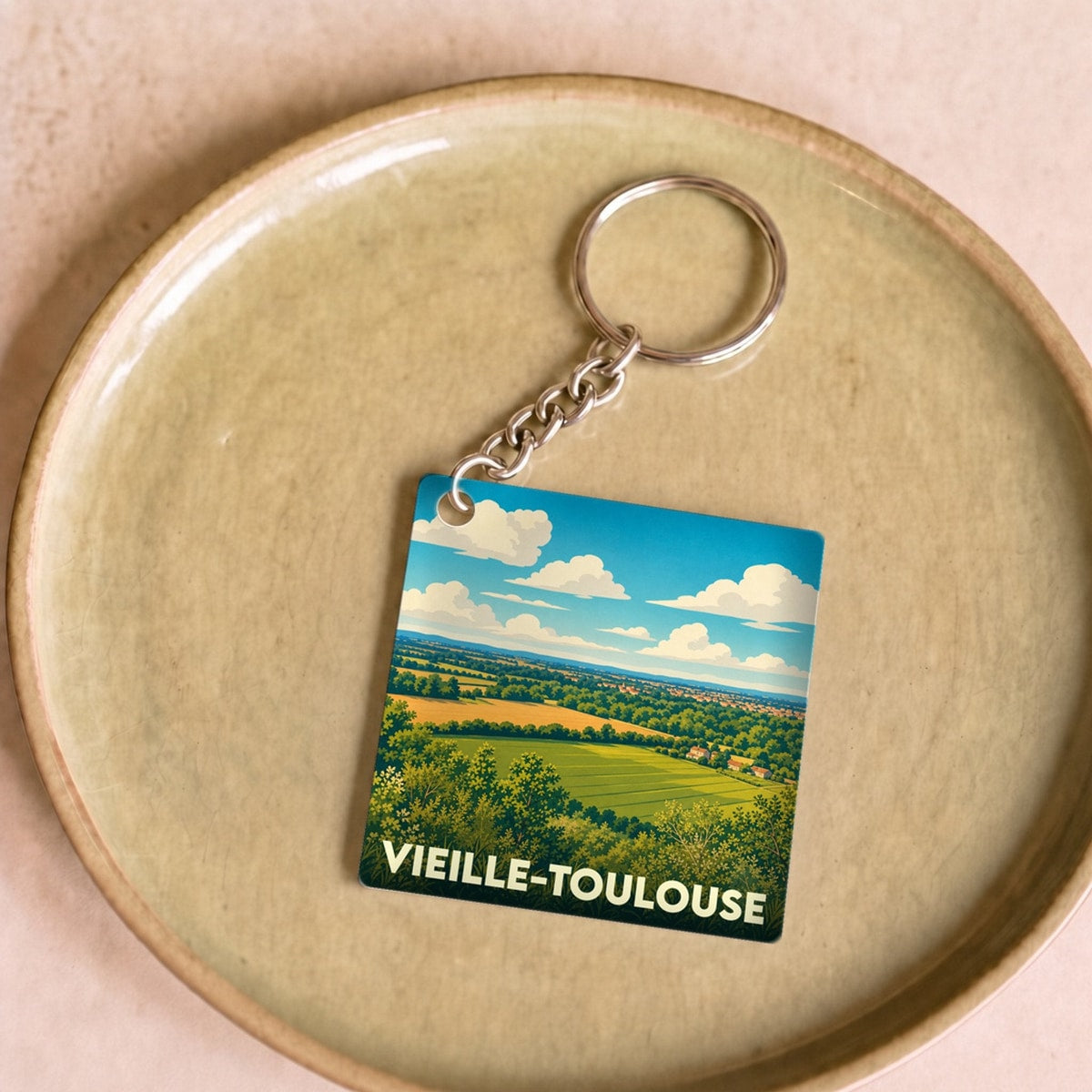 Porte-clés souvenir de Vieille-Toulouse illustré par un paysage de collines verdoyantes sous un ciel nuageux.