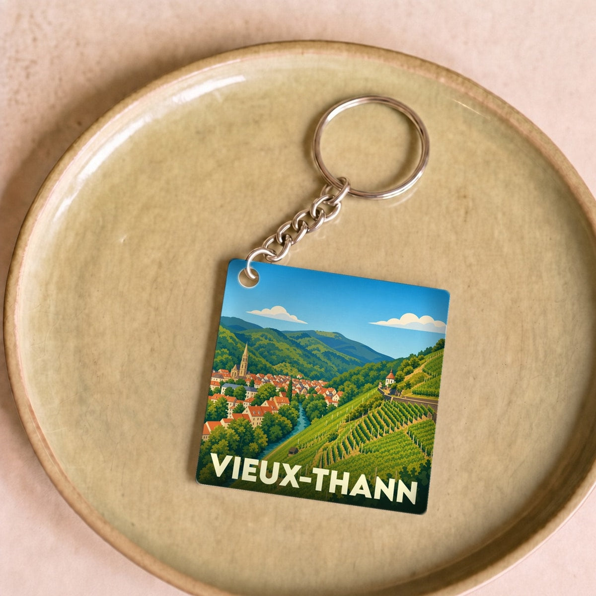 Porte-clés souvenir de la ville de Vieux-Thann avec une illustration stylisée d'un paysage de vignobles.