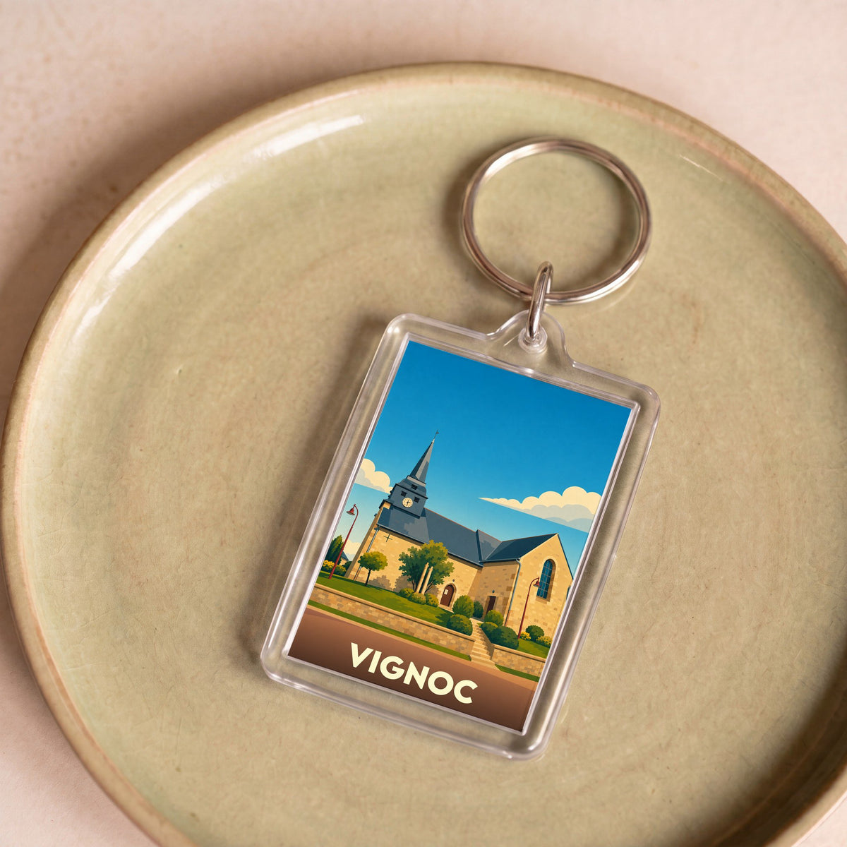Porte-clés souvenir de la ville de Vignoc avec une illustration stylisée de son église.