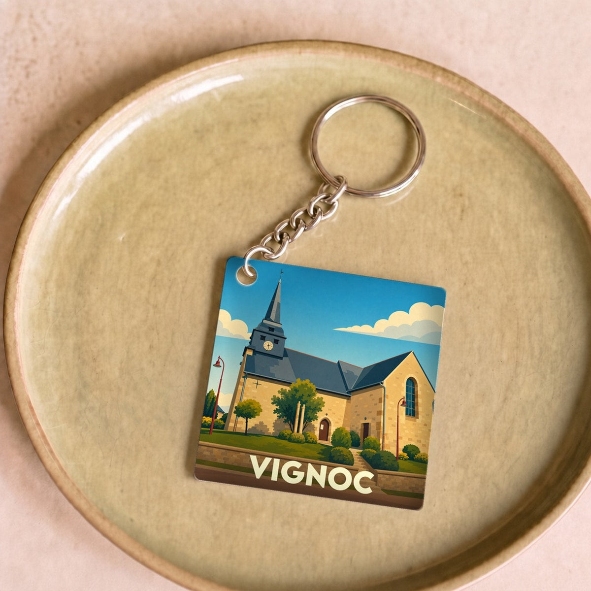 Porte-clés souvenir de la ville de Vignoc avec une illustration stylisée de son église.