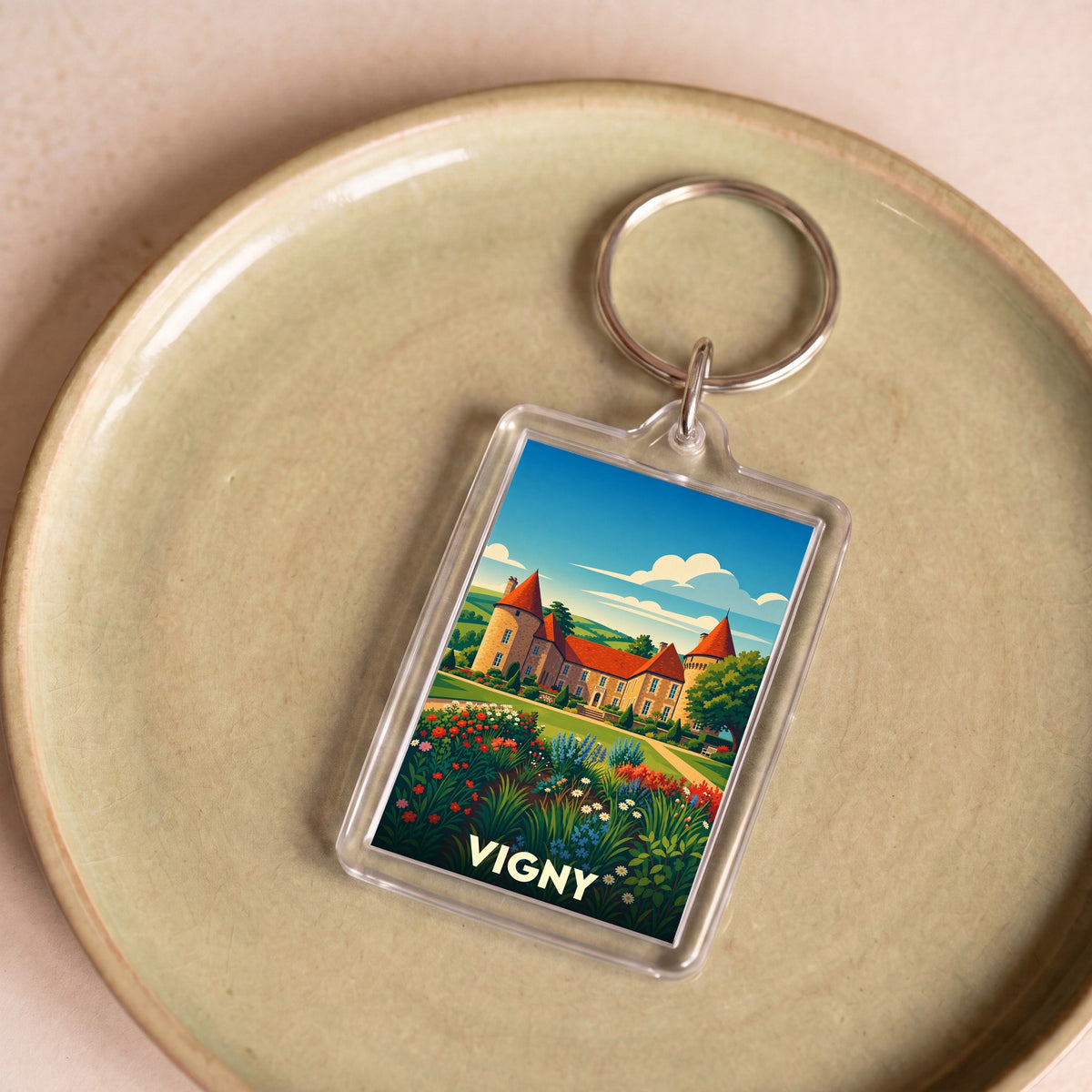 Porte-clés souvenir de la ville de Vigny avec une illustration stylisée de son château et de ses jardins.