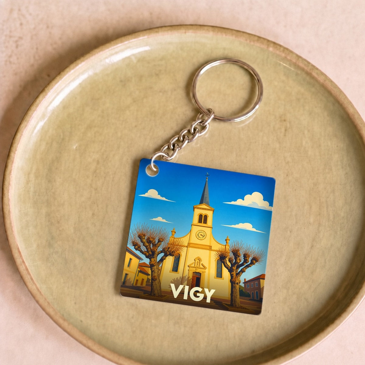 Porte-clés souvenir de la ville de Vigy avec une illustration stylisée de son église.