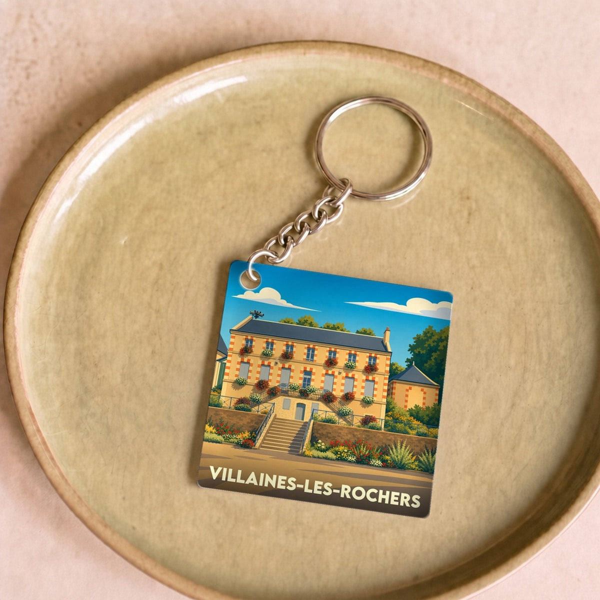 Porte-clés souvenir de la ville de Villaines-les-Rochers avec une illustration colorée et stylisée.
