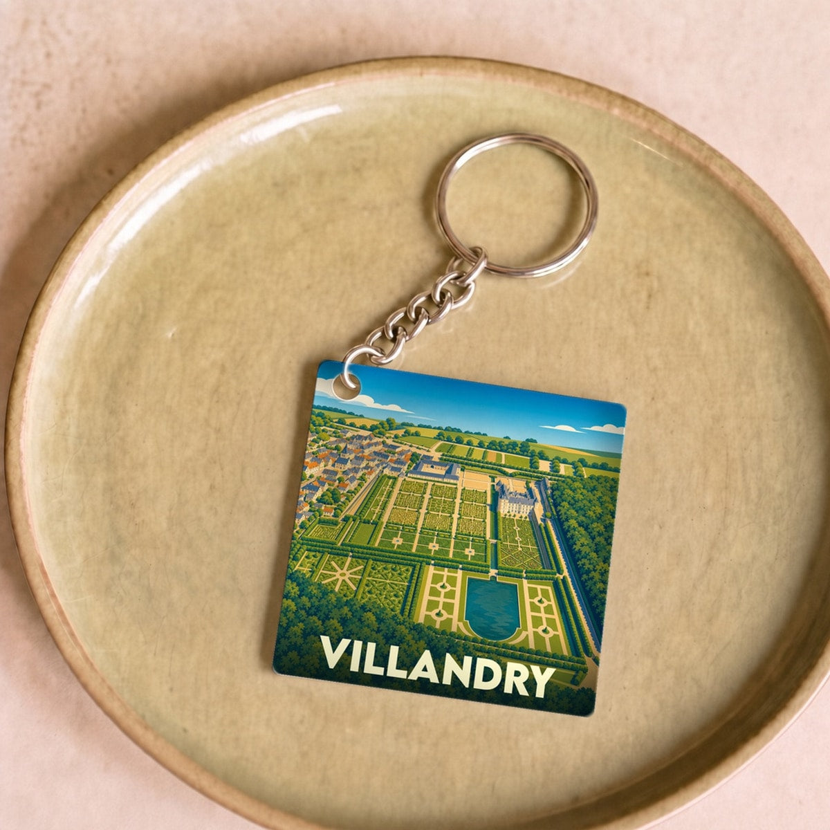 Porte-clés souvenir de la ville de Villandry avec une illustration stylisée de ses jardins.