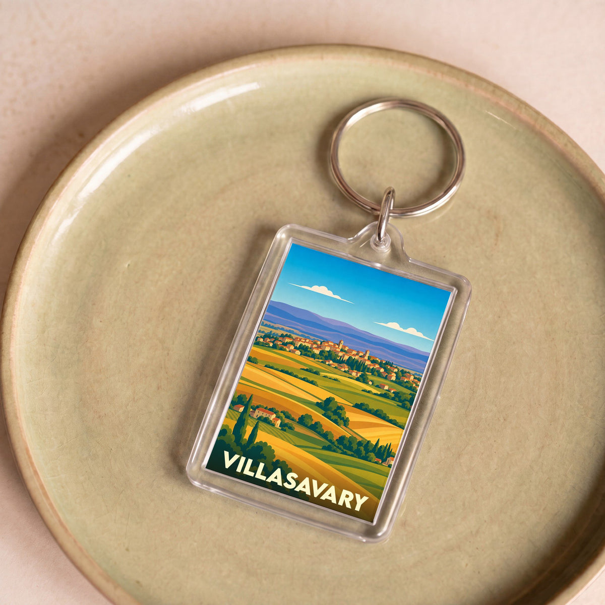 Porte-clés souvenir de la ville de Villasavary avec une illustration stylisée de paysages vallonnés.