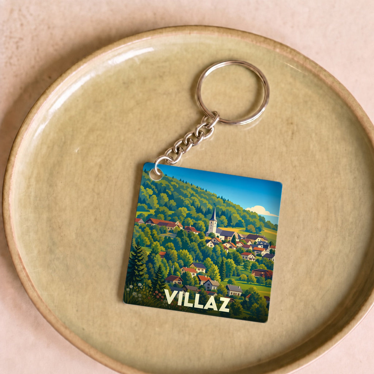 Porte-clés souvenir de la ville de Villaz avec une illustration stylisée de son village et de ses montagnes.