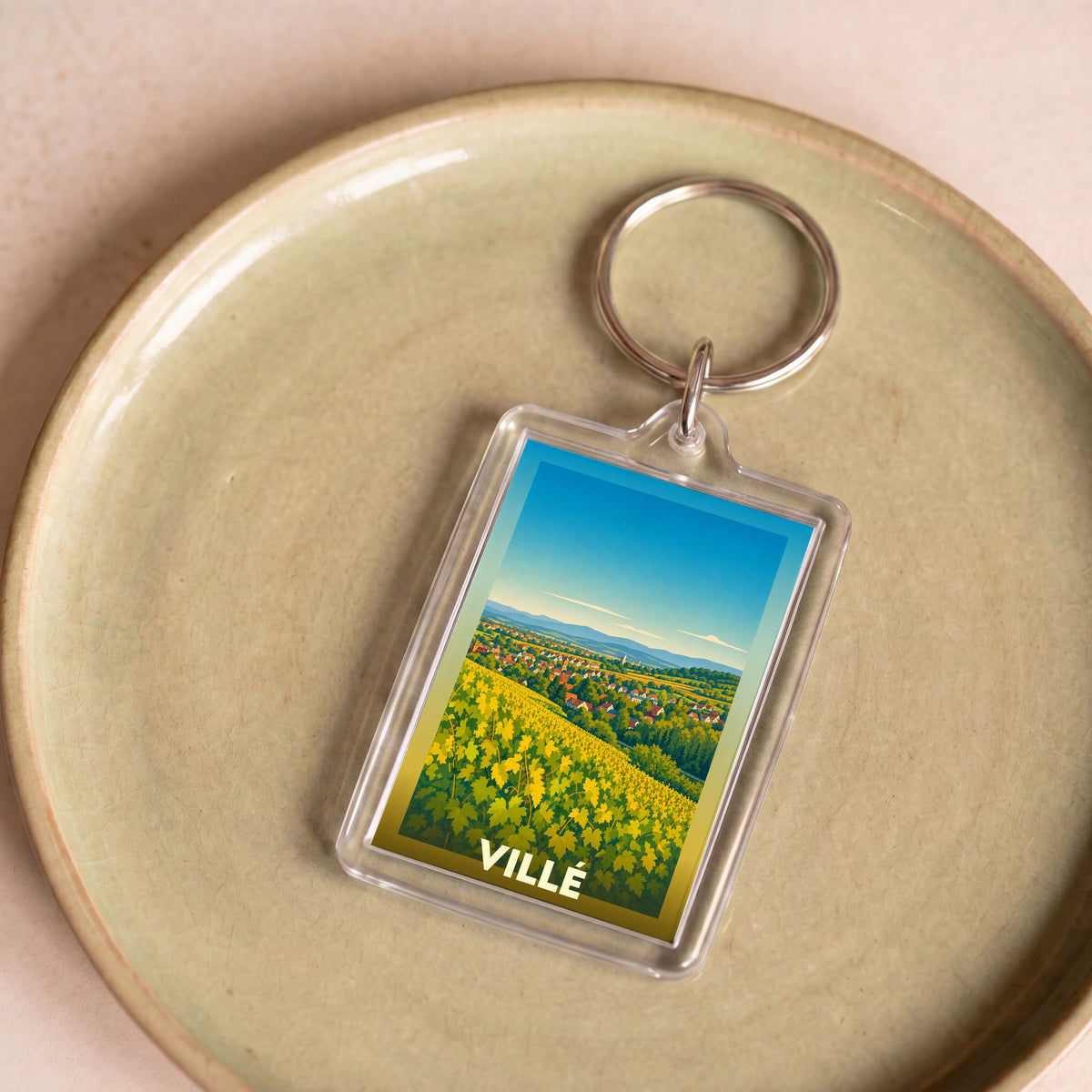 Porte-clés souvenir de la ville de Villé avec une illustration stylisée de vignobles ensoleillés.