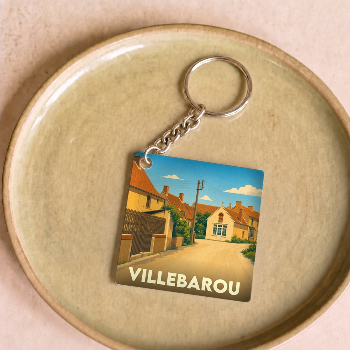 Porte-clés souvenir de la ville de Villebarou avec une illustration stylisée d'une rue ensoleillée.