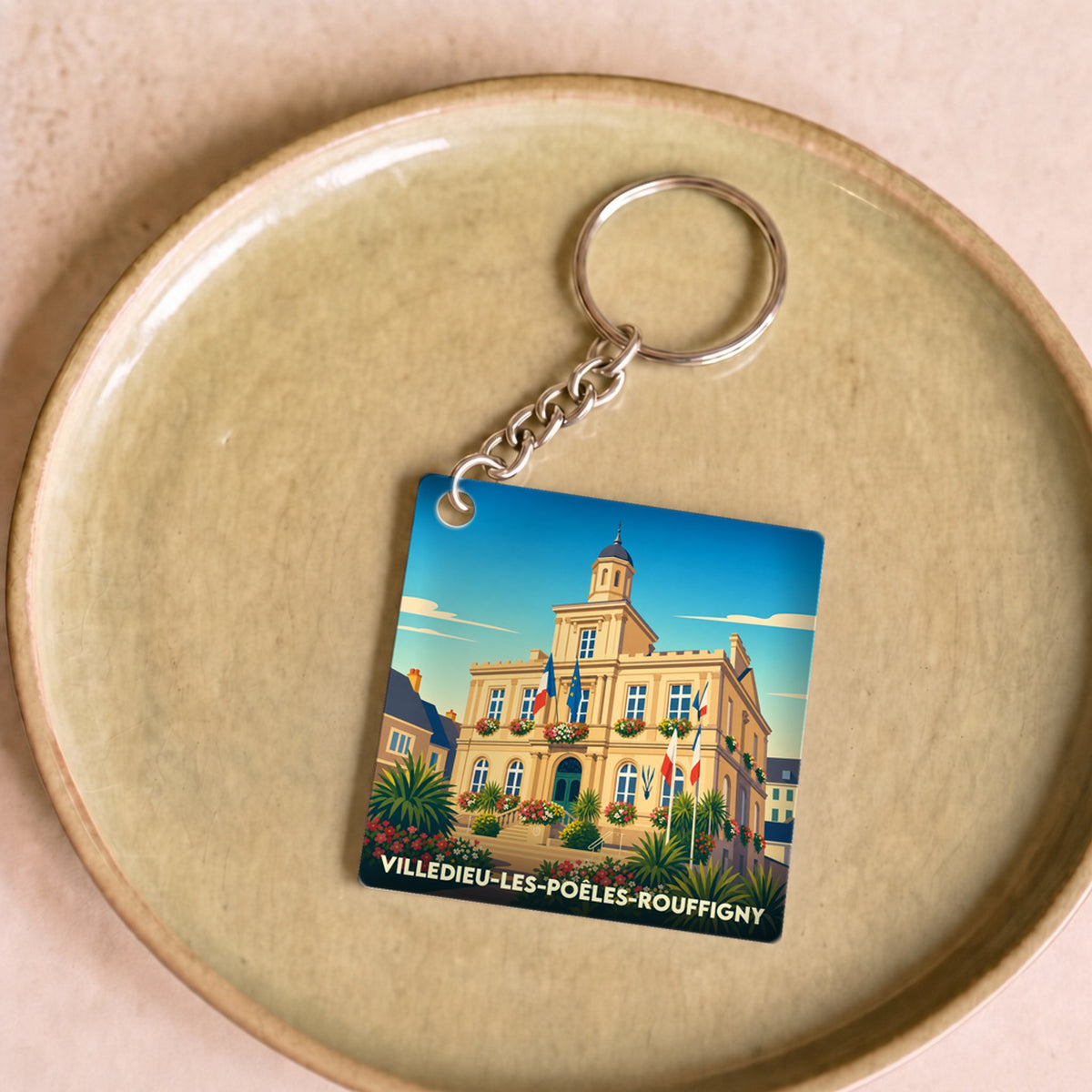 Porte-clés souvenir de la ville de Villedieu-les-Poêles-Rouffigny avec une illustration stylisée de son hôtel de ville.