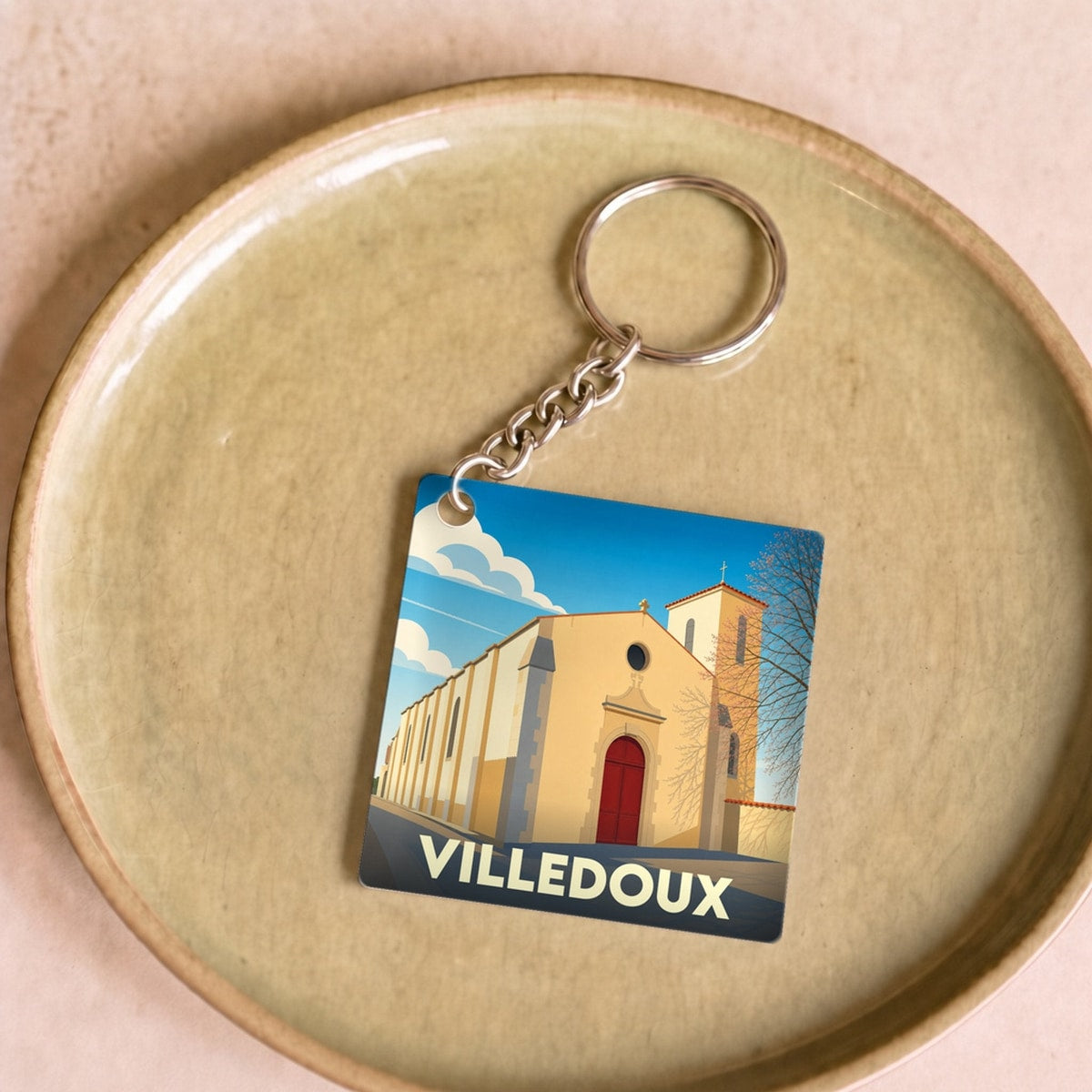 Porte-clés souvenir de la ville de Villedoux avec une illustration stylisée de son église.
