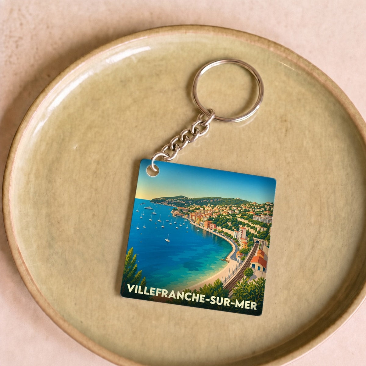 Porte-clés souvenir de la ville de Villefranche-sur-Mer avec une illustration stylisée de sa baie.