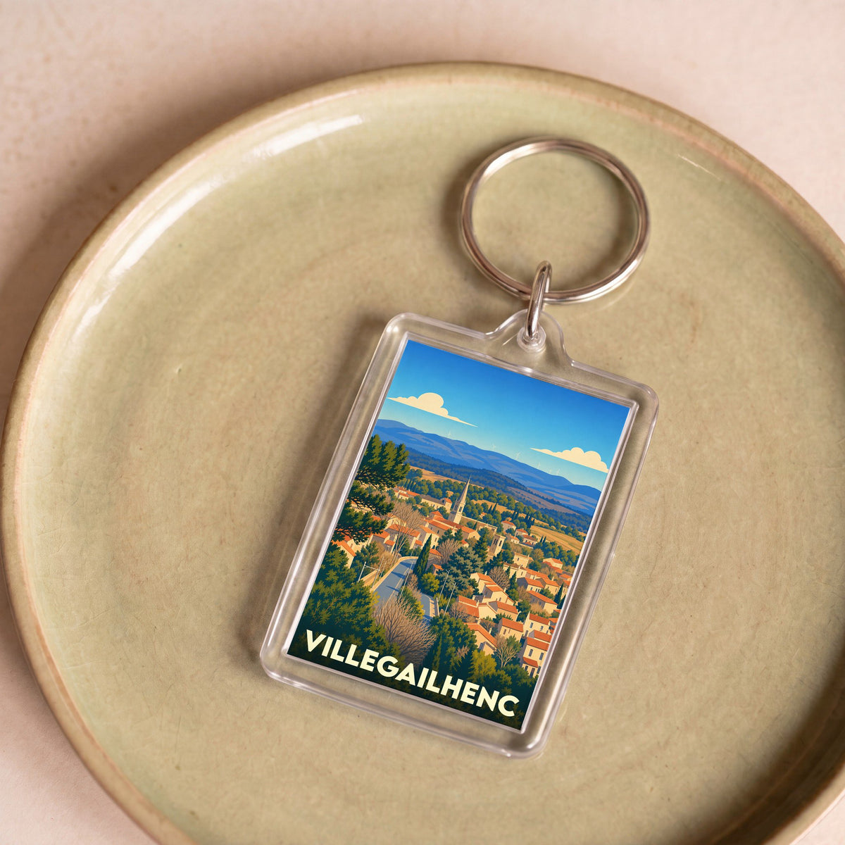 Porte-clés souvenir de la ville de Villegailhenc avec une illustration stylisée de son paysage urbain.