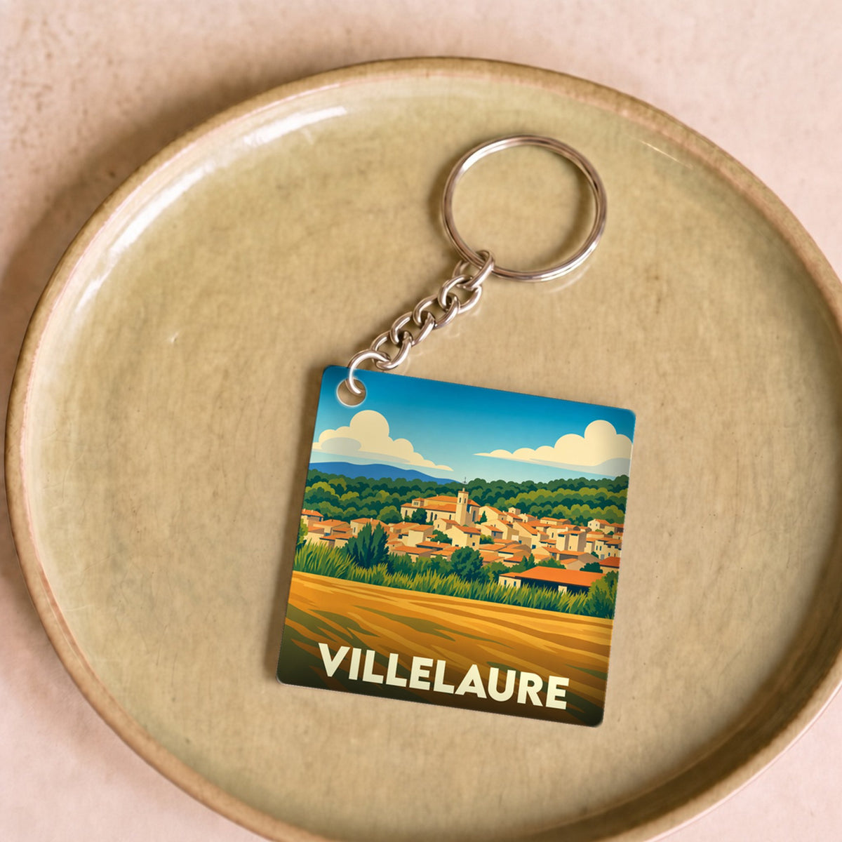 Porte-clés souvenir de la ville de Villelaure avec une illustration stylisée de son paysage provençal.