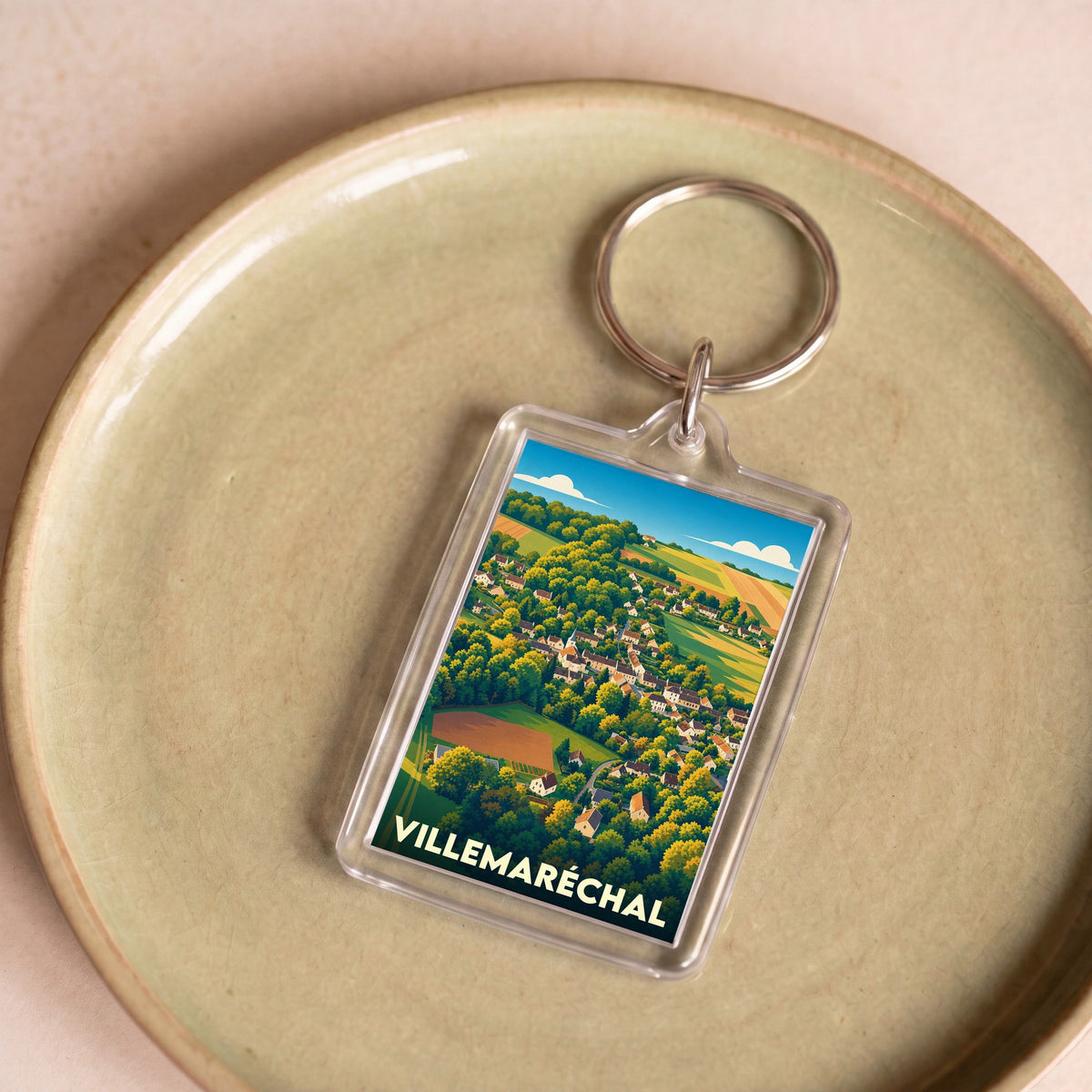 Porte-clés souvenir de la ville de Villemaréchal avec une illustration stylisée de son paysage vallonné.