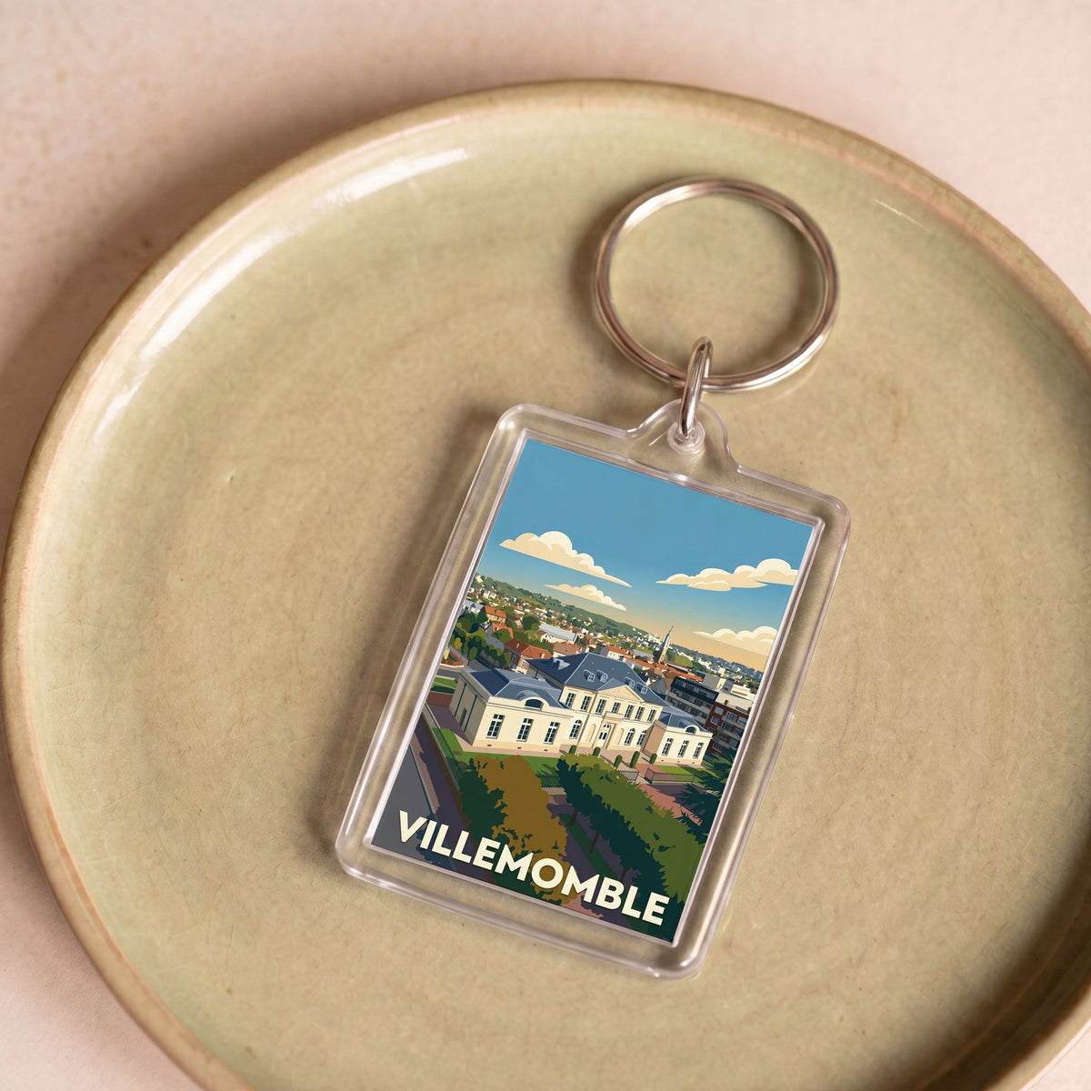 Porte-clés souvenir de la ville de Villemomble avec une illustration stylisée.