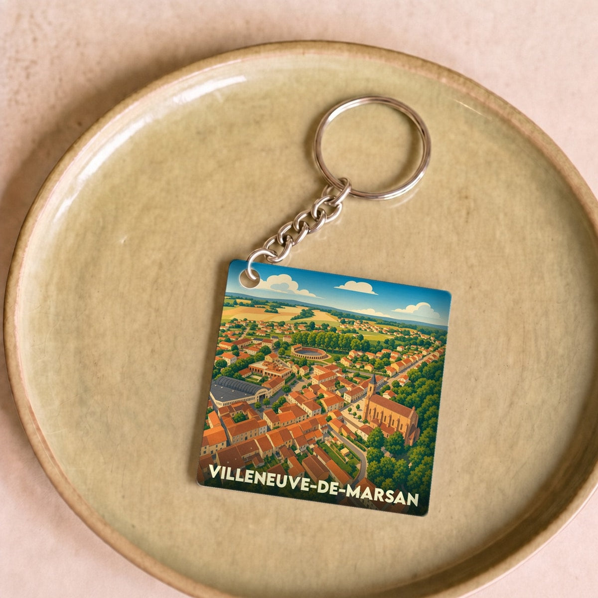 Porte-clés souvenir de la ville de Villeneuve-de-Marsan avec une illustration aérienne colorée et stylisée.