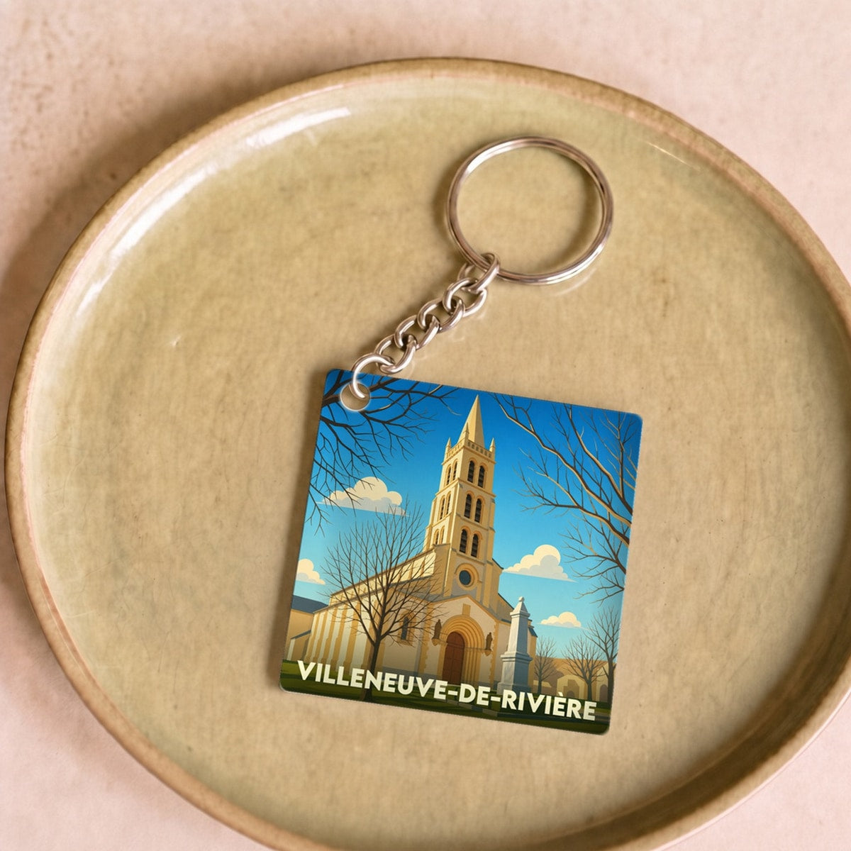 Porte-clés souvenir de la ville de Villeneuve-de-Rivière avec une illustration stylisée de son église.