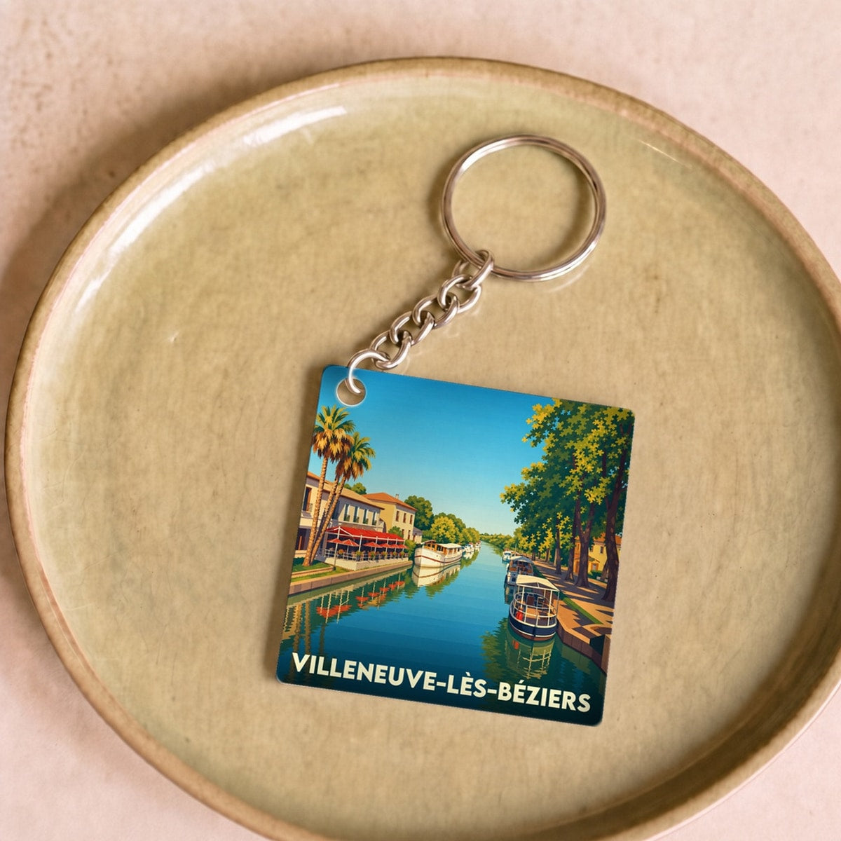 Porte-clés souvenir de la ville de Villeneuve-lès-Béziers avec une illustration stylisée du canal et de ses bateaux.