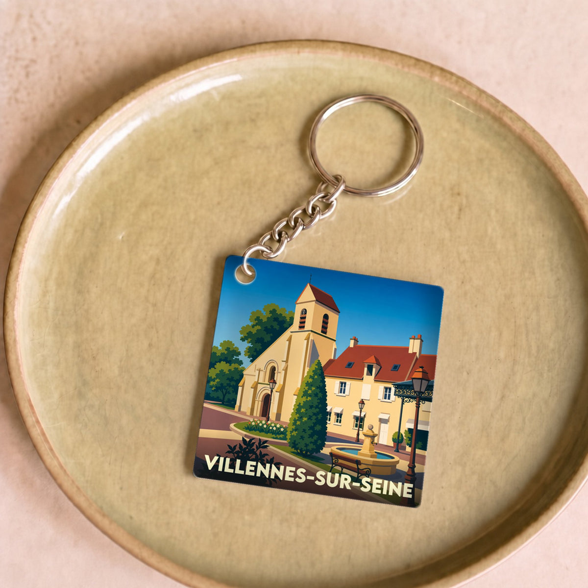 Porte-clés souvenir de la ville de Villennes-sur-Seine avec une illustration stylisée de son église et d'une place.