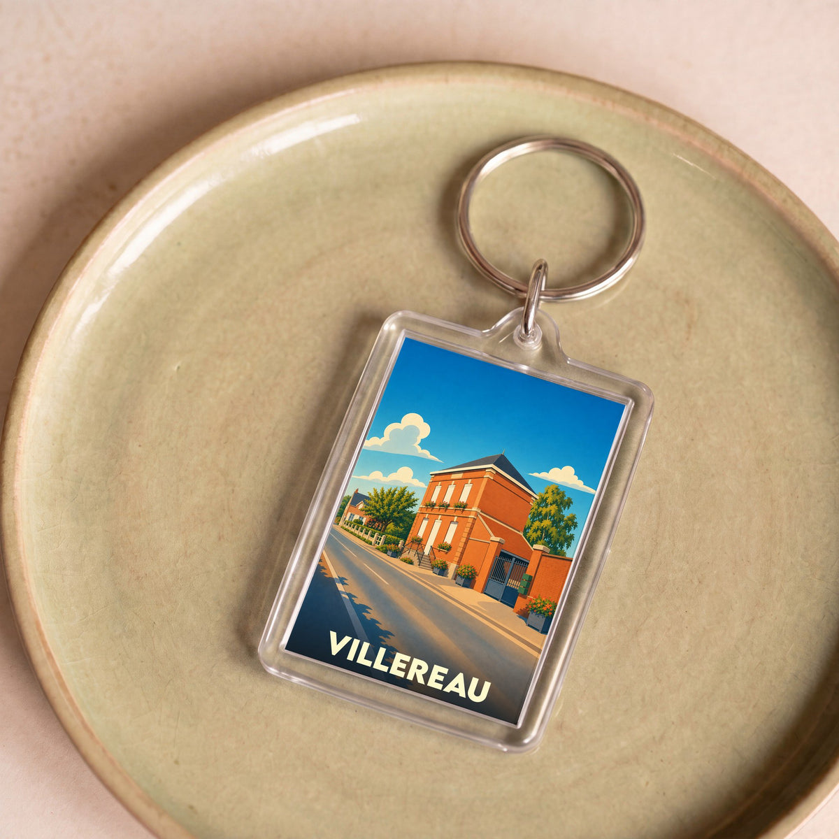 Porte-clés souvenir de la ville de Villereau avec une illustration stylisée d'une rue ensoleillée.