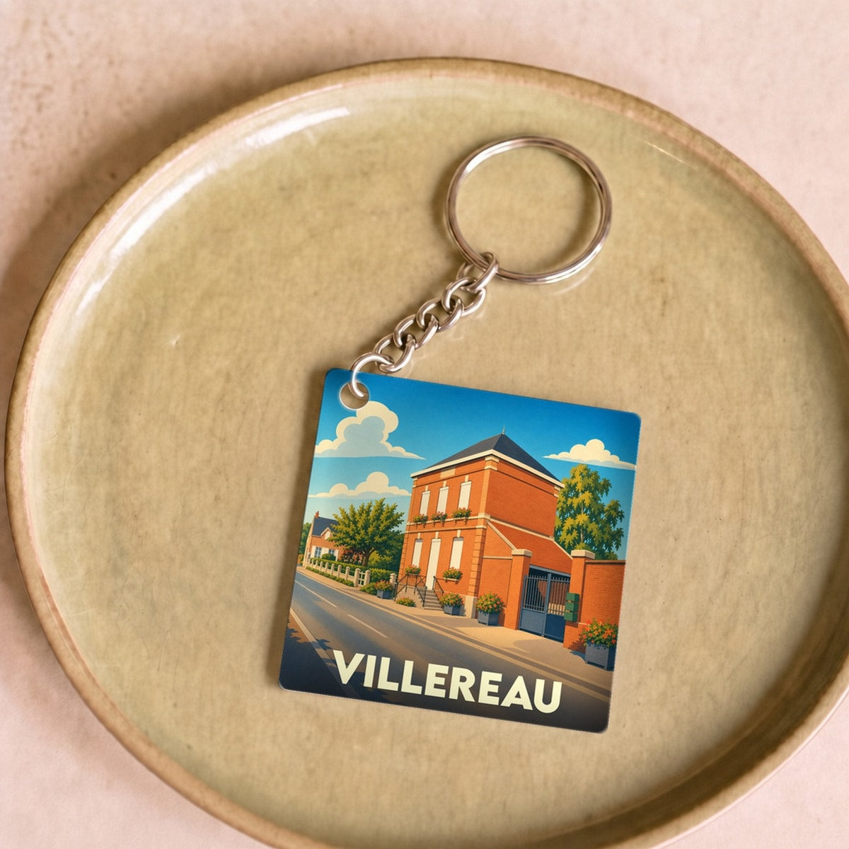 Porte-clés souvenir de la ville de Villereau avec une illustration stylisée d'une rue ensoleillée.