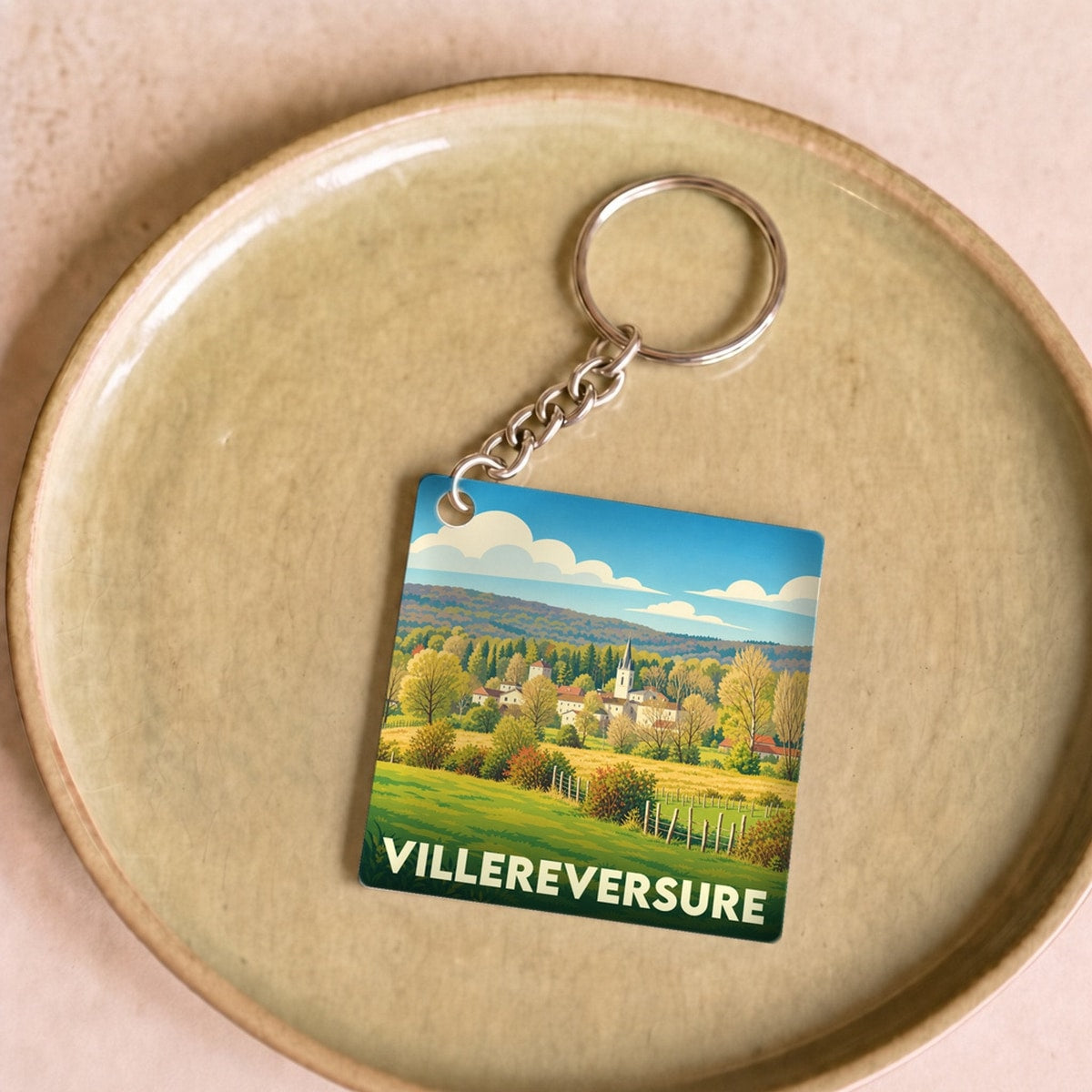 Porte-clés souvenir de la ville de Villereversure avec une illustration stylisée de son paysage champêtre.