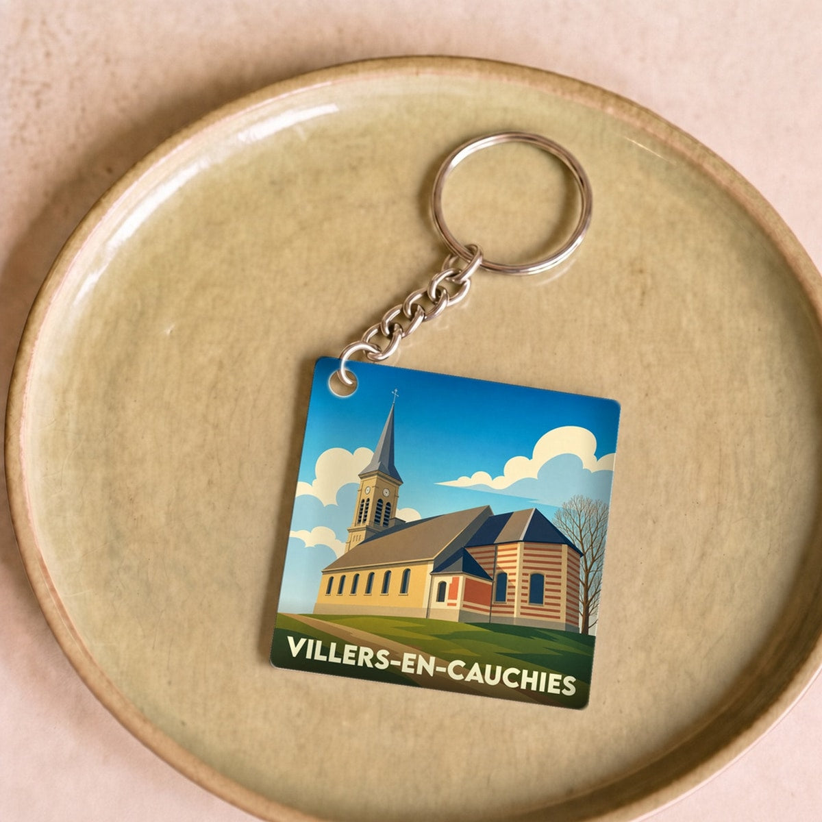 Porte-clés souvenir de Villers-en-Cauchies avec une illustration stylisée de son église.