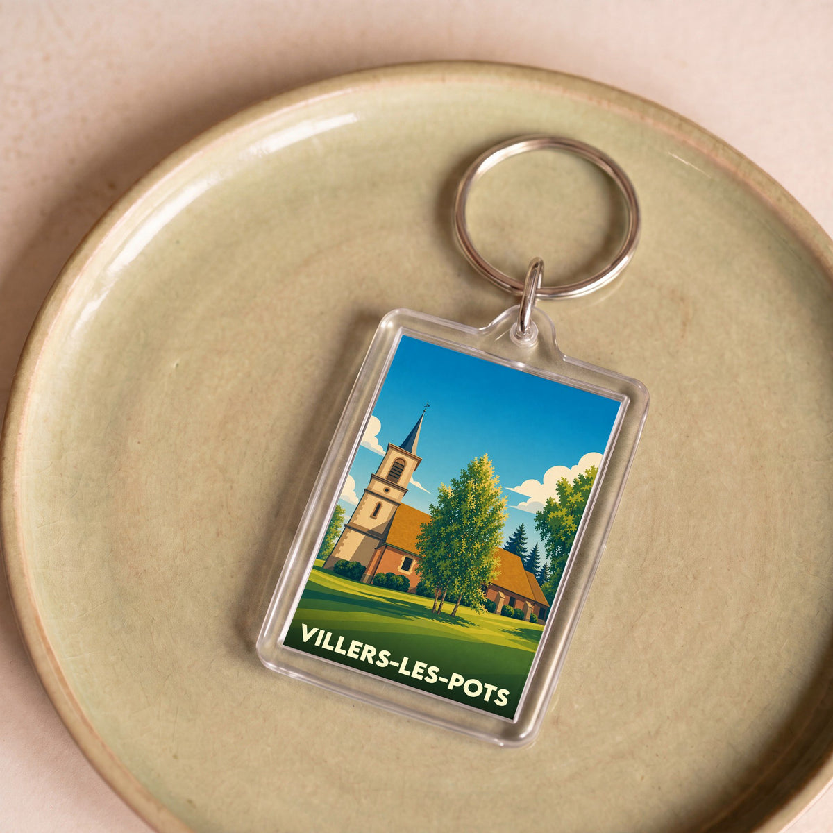 Porte-clés souvenir de la ville de Villers-les-Pots avec une illustration stylisée de son église.
