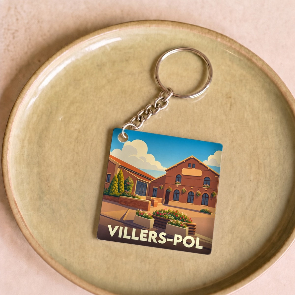 Porte-clés souvenir de la ville de Villers-Pol avec une illustration stylisée d'un bâtiment en briques.