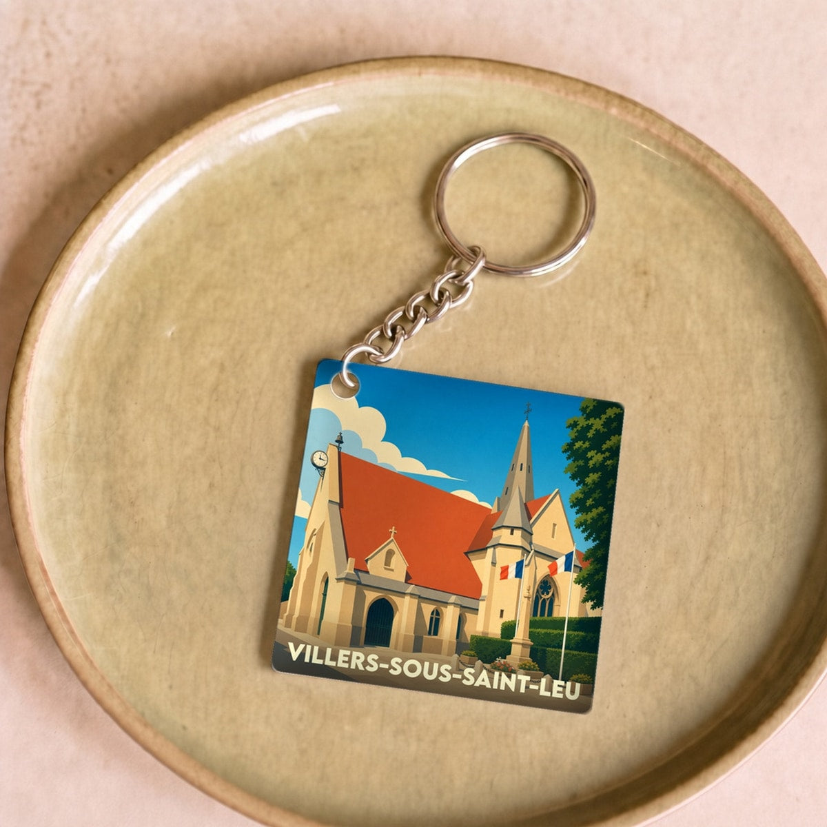 Porte-clés souvenir de Villers-sous-Saint-Leu présentant une illustration stylisée de son église sous un ciel bleu.