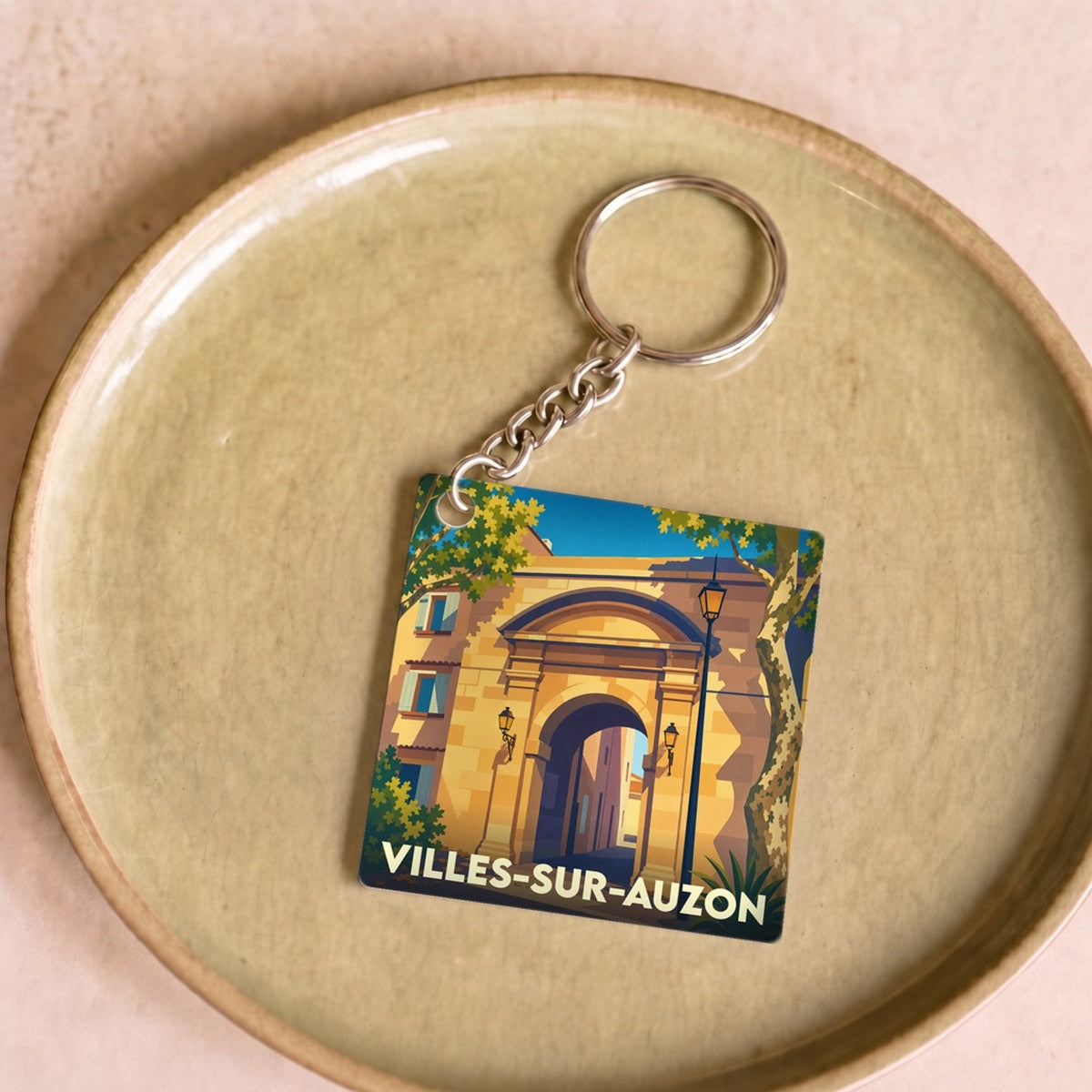 Porte-clés souvenir de la ville de Villes-sur-Auzon avec une illustration stylisée d'un porche en pierre.