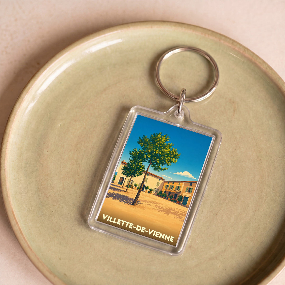 Porte-clés souvenir de la ville de Villette-de-Vienne avec une illustration stylisée d'une place ensoleillée.