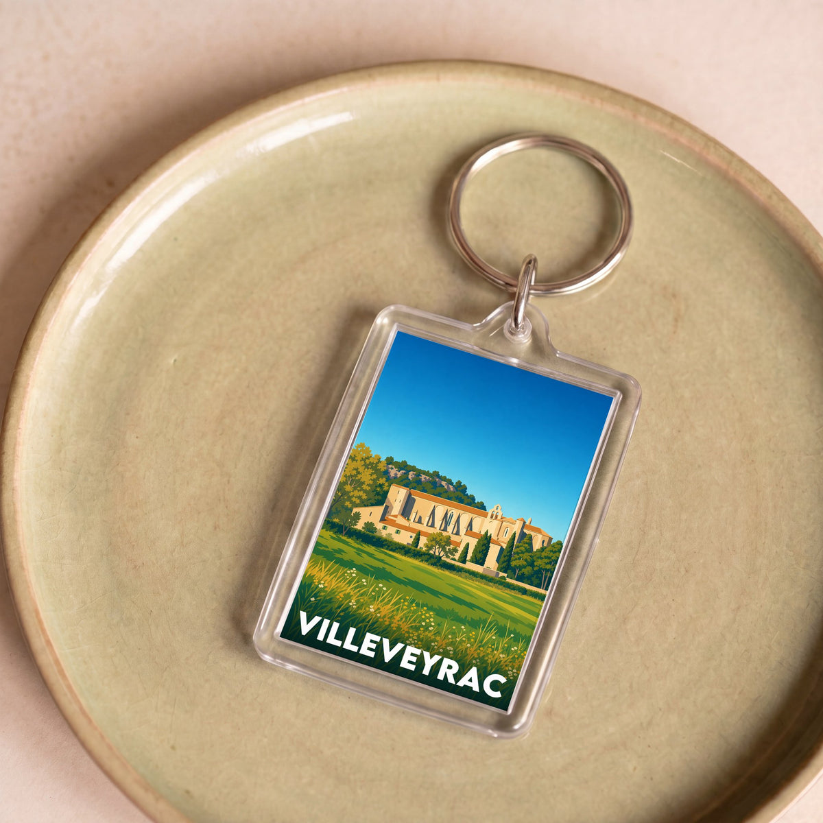 Porte-clés souvenir de la ville de Villeveyrac avec une illustration stylisée.