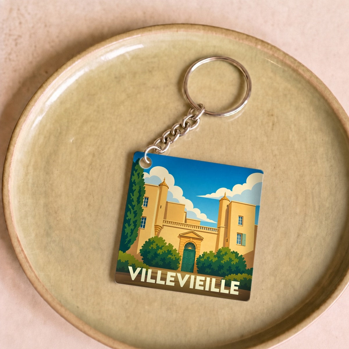 Porte-clés souvenir de la ville de Villevieille avec une illustration stylisée du château local.