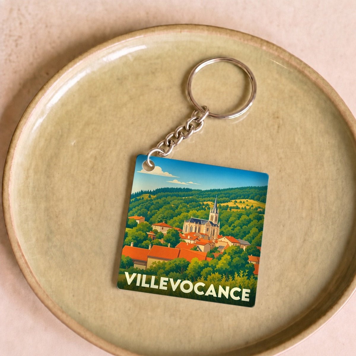 Porte-clés souvenir de la ville de Villevocance avec une illustration stylisée du village.