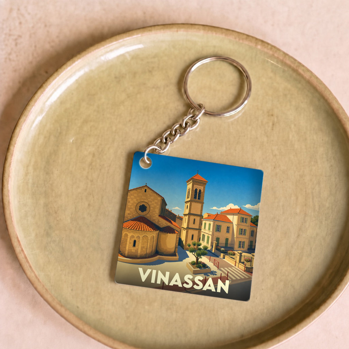 Porte-clés souvenir de la ville de Vinassan avec une illustration stylisée.