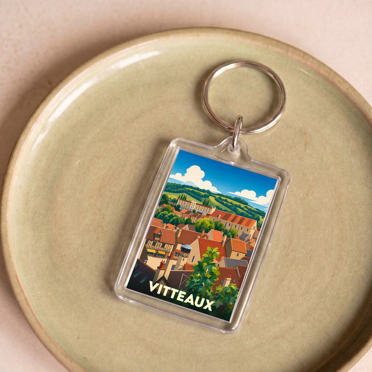 Porte-clés souvenir de la ville de Vitteaux avec une illustration stylisée d'un paysage urbain.