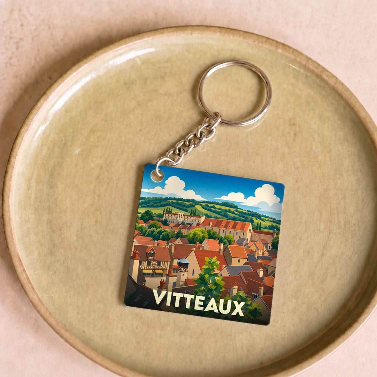 Porte-clés souvenir de la ville de Vitteaux avec une illustration stylisée d'un paysage urbain.