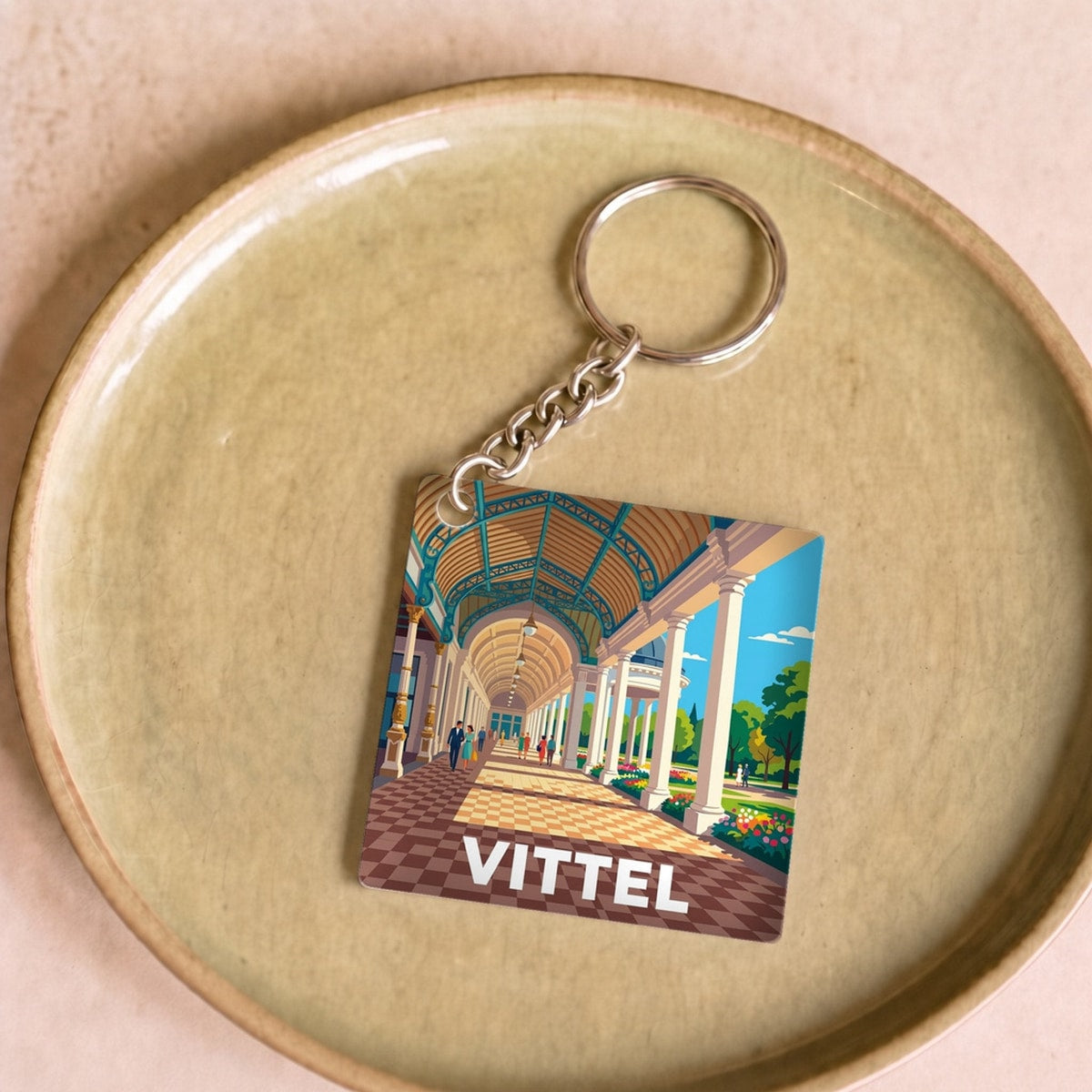 Porte-clés souvenir de la ville de Vittel avec une illustration stylisée.