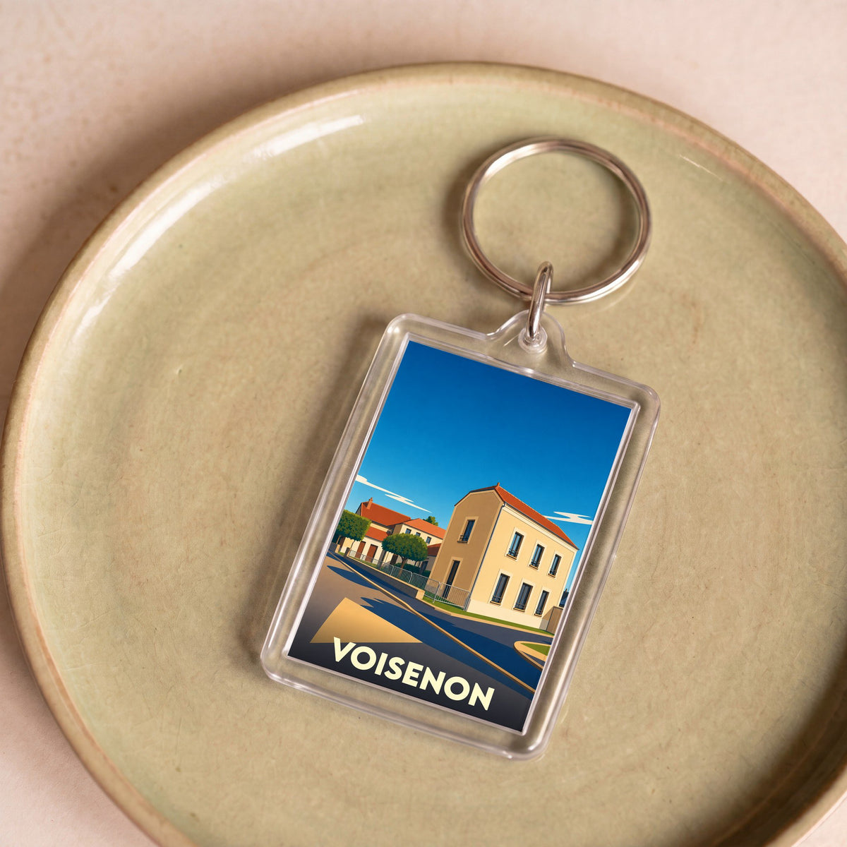 Porte-clés souvenir de la ville de Voisenon avec une illustration stylisée.