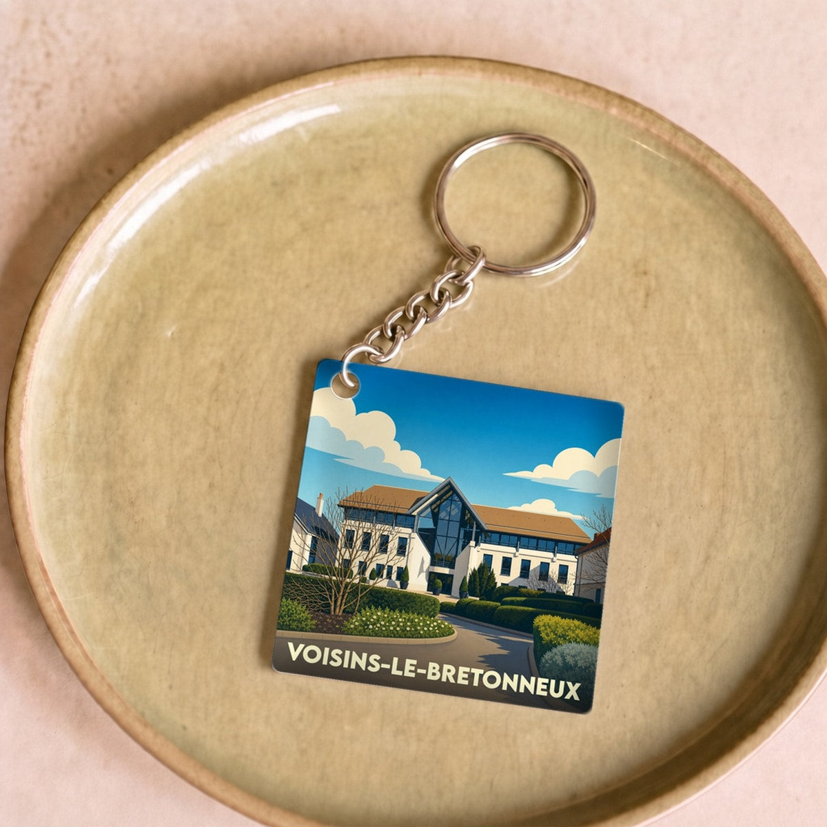 Porte-clés souvenir de la ville de Voisins-le-Bretonneux avec une illustration stylisée.