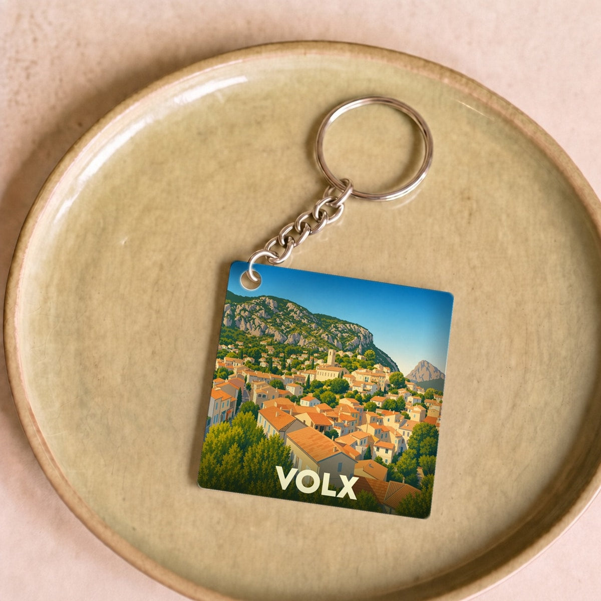 Porte-clés souvenir de la ville de Volx avec une illustration stylisée de ses paysages provençaux.